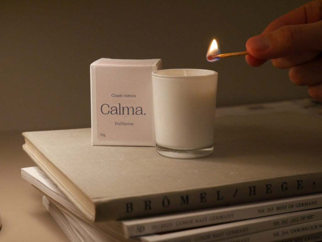 Weiße Duftkerze im Glas Calma Clean Cotton wird angezündet – Duftkerze für Zuhause, Wellness, Selfcare und Geschenkidee
