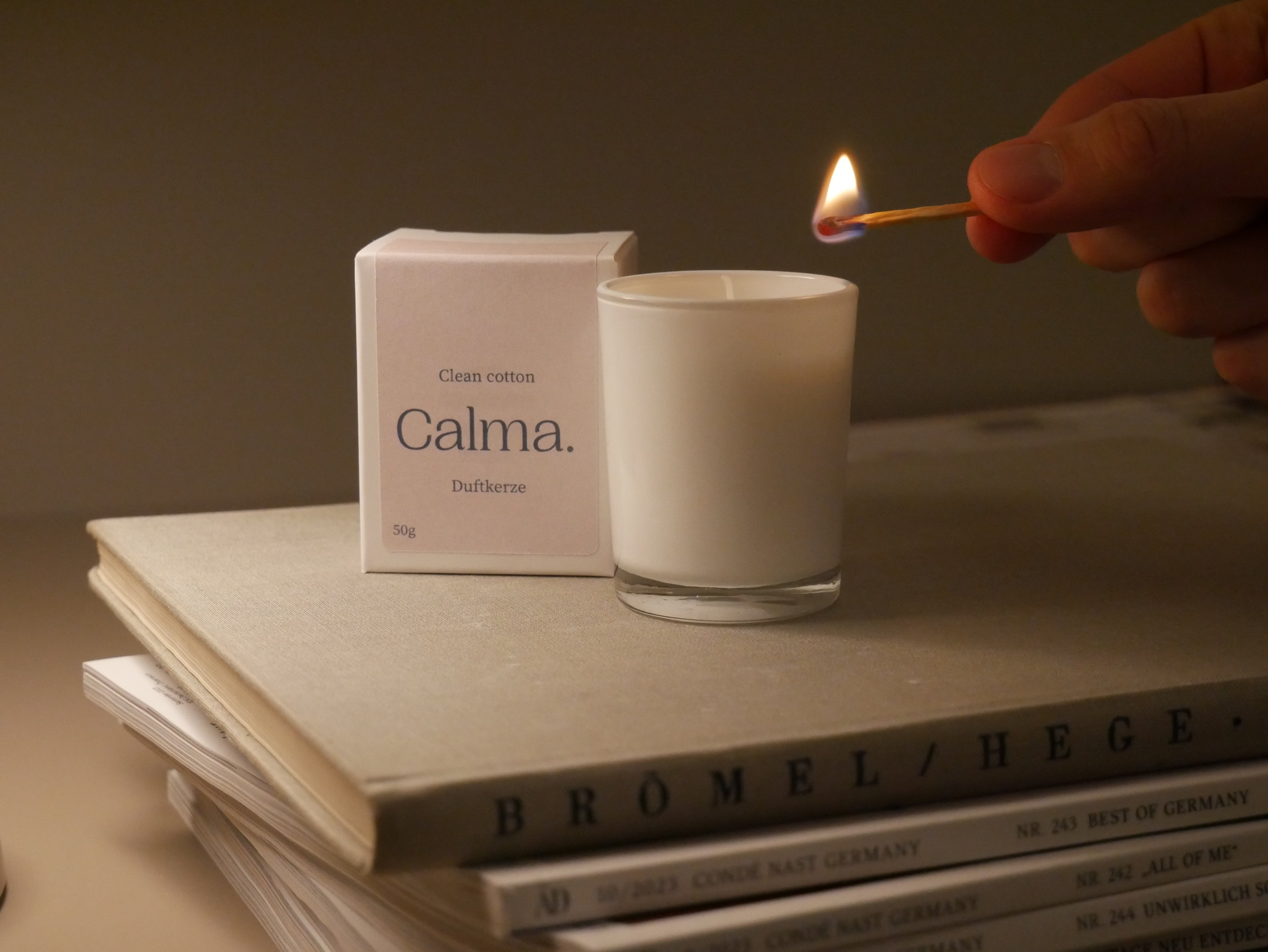 Weiße Duftkerze im Glas Calma Clean Cotton wird angezündet – Duftkerze für Zuhause, Wellness, Selfcare und Geschenkidee